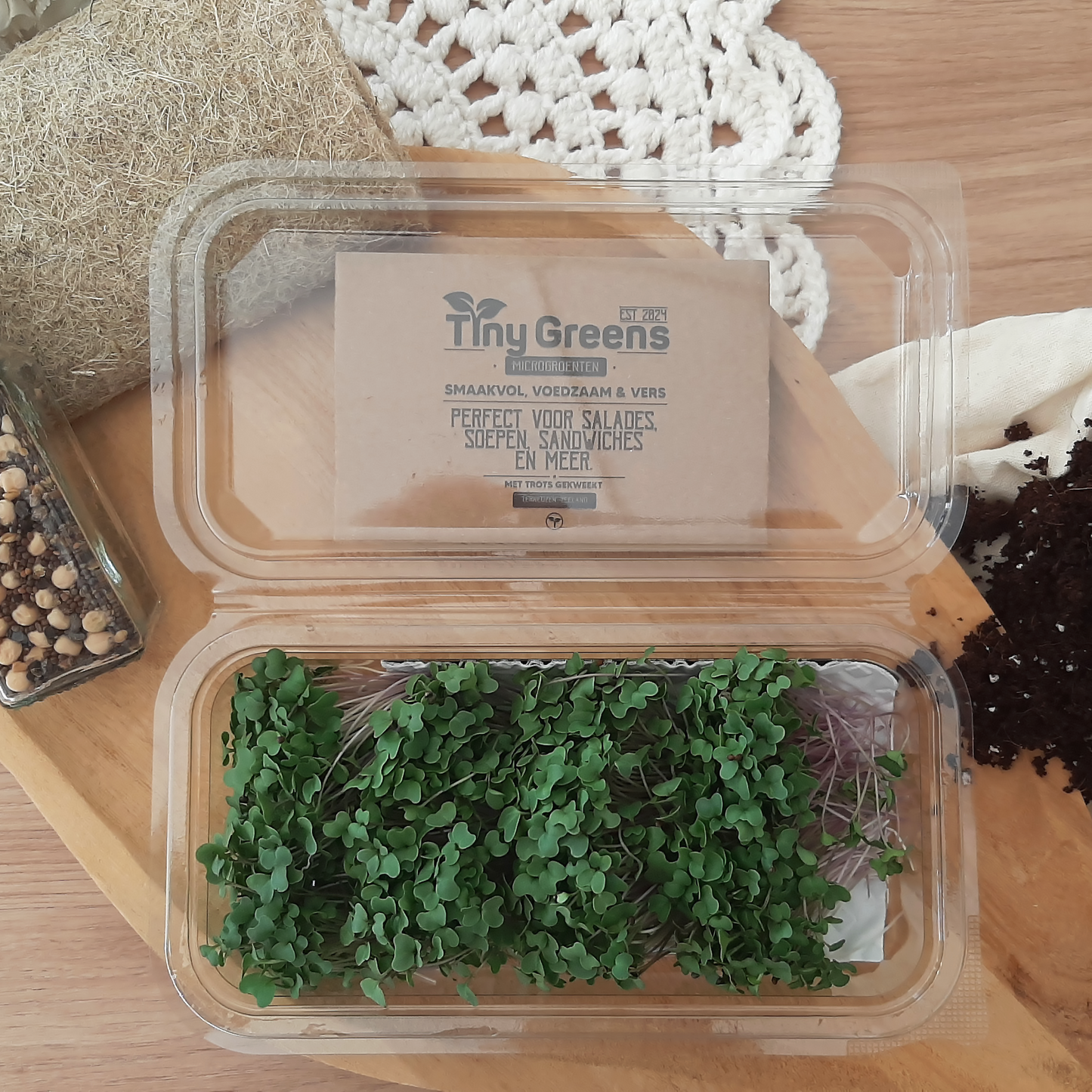 Natuurlijke broccoli cress van TinyGreens, biologisch verantwoord geteeld en rijk aan voedingsstoffen, perfect voor salades en als garnering. Gepresenteerd als bovenaanzicht in doorzichtig plastic schaal, met het label van TinyGreens er zichtbaar achter.